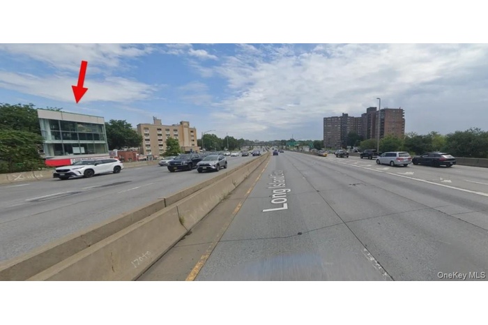 View of asphalt road with street lighting, sidewalks, a view of city, and curbs