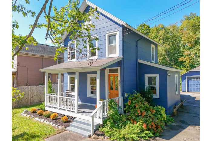 Traditional-style house with covered porch, a detached garage, and an outdoor structure