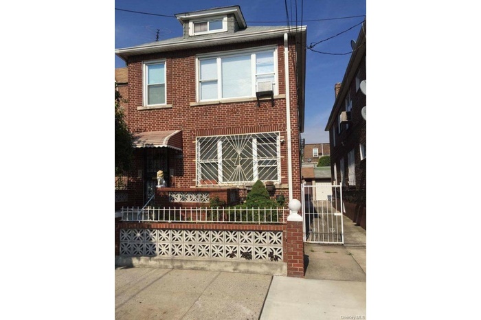 View of front of home featuring brick siding, a fenced front yard, and a gate