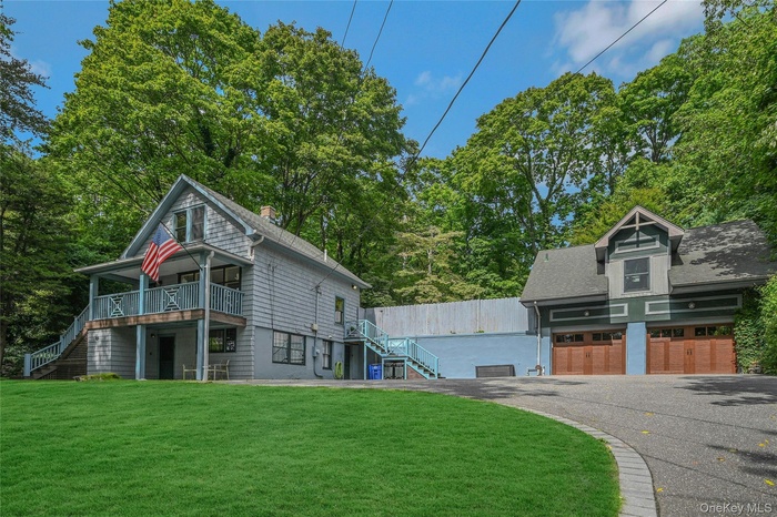 View of side of home featuring stairs, a lawn, asphalt driveway, and a shingled roof