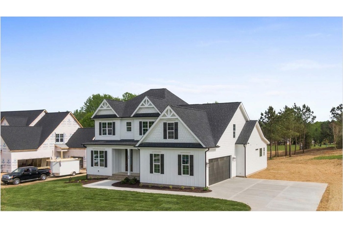 View of front facade featuring board and batten siding, concrete driveway, a garage, a front yard, and roof with shingles