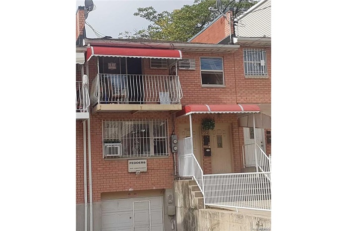 View of front of house featuring brick siding, a balcony, and a garage