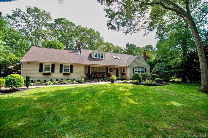 Cape cod home with a chimney, a porch, a front yard, and a shingled roof