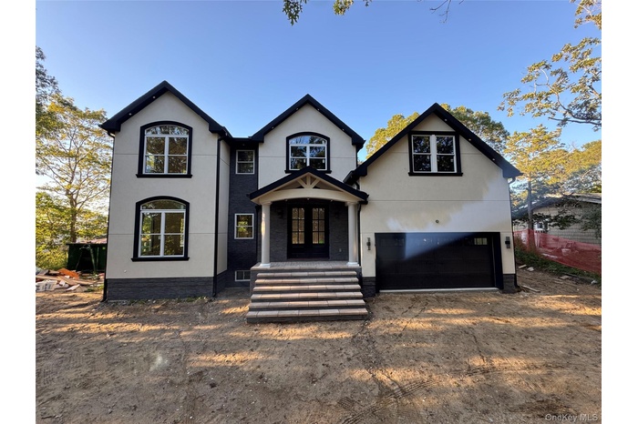 View of front of property with stucco siding, french doors, driveway, and an attached garage
