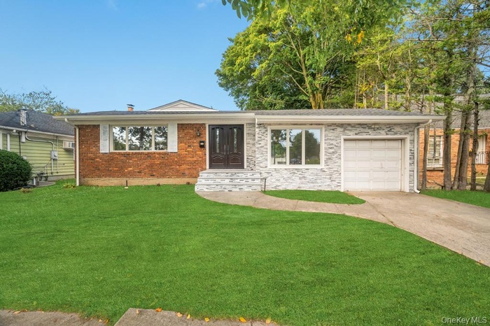 Ranch-style home featuring a garage, driveway, a front yard, and brick siding