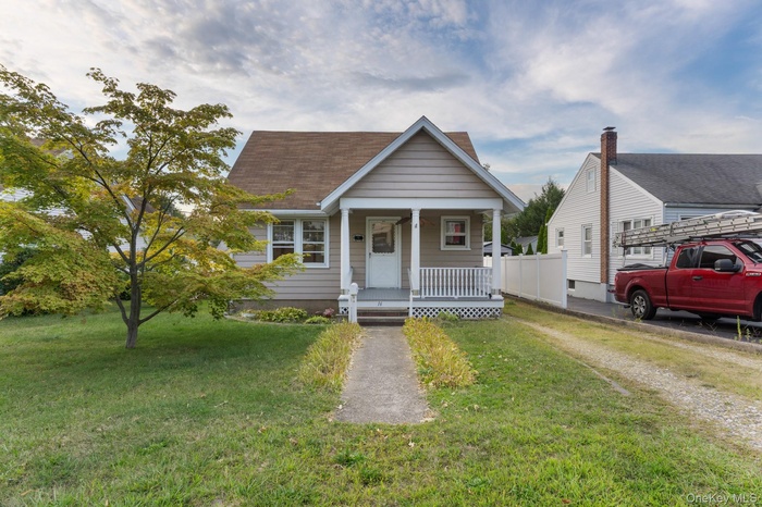 Bungalow-style home featuring a porch, roof with shingles, and a front yard