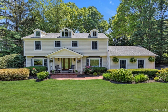 View of front of property with a porch, a shingled roof, and a front yard