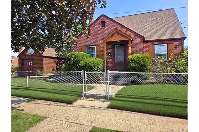View of front of property featuring a gate, a shingled roof, brick siding, and a fenced front yard