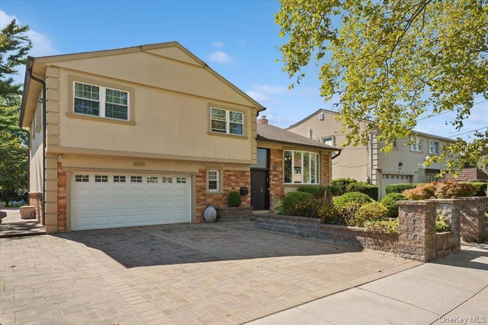 View of front facade featuring a garage, decorative driveway, stucco siding, and brick siding
