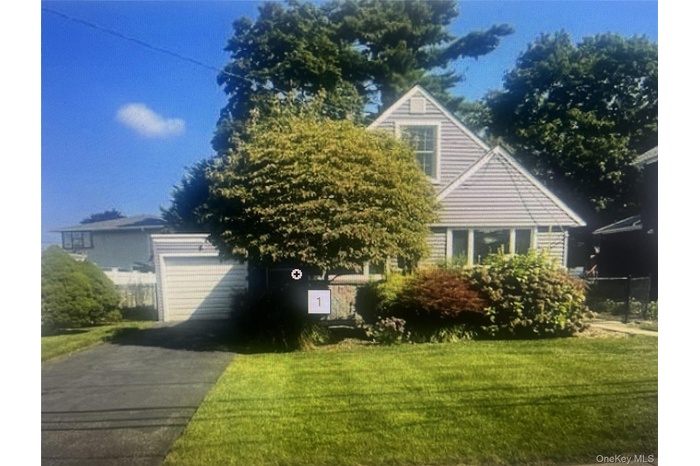 View of front of home with a lawn, driveway, and an attached garage