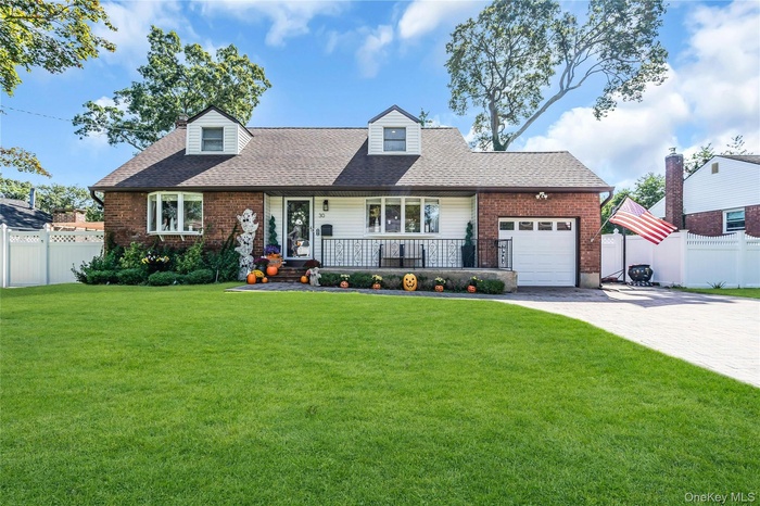 New england style home with a shingled roof, decorative driveway, a porch, and brick siding