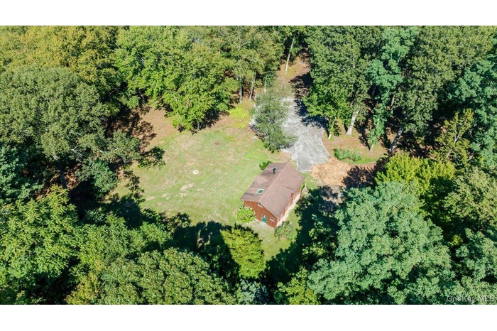 Aerial view of property and surrounding area featuring a forest