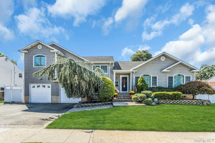 View of front facade with asphalt driveway, a front yard, and an attached garage