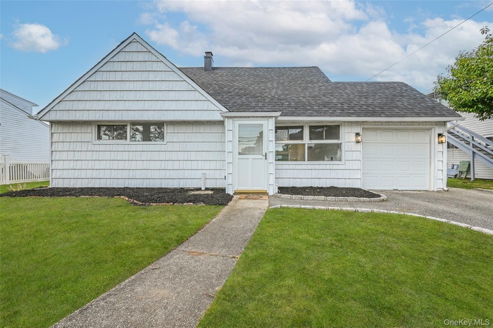 View of front of house featuring a shingled roof, a front lawn, a chimney, and an attached garage