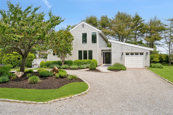 View of front of home featuring a garage and gravel driveway