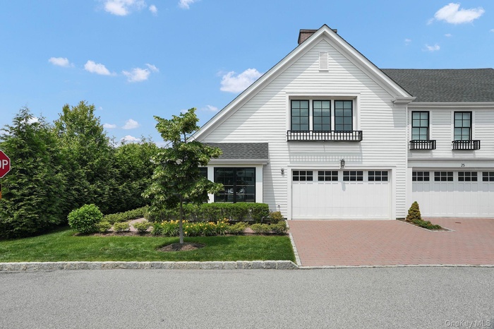 View of front of house with decorative driveway, a garage, a chimney, and a shingled roof