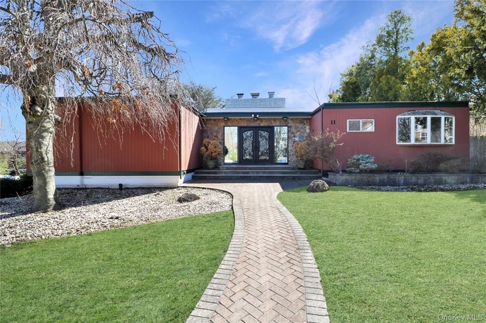 Rear view of property with french doors, a lawn, and solar panels