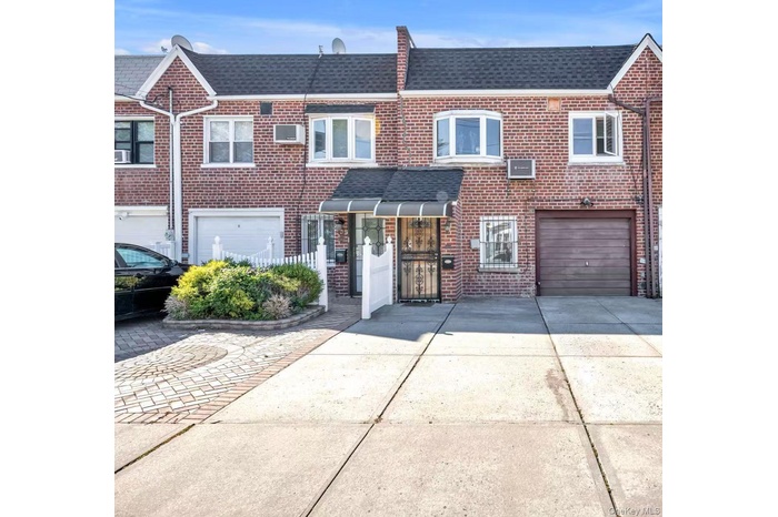 Traditional-style home featuring driveway, brick siding, a shingled roof, and a garage