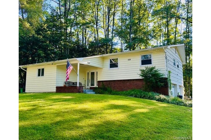 Tri-level home featuring a front yard and brick siding