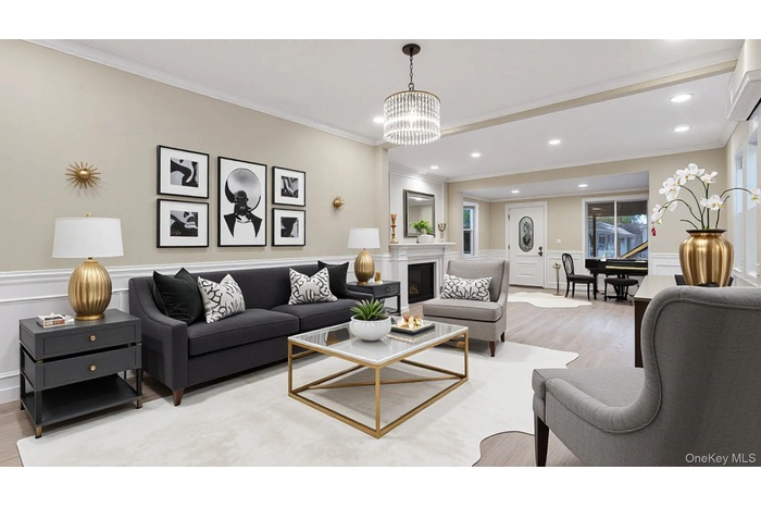 Living area with crown molding, wood finished floors, a decorative wall, wainscoting, and a glass covered fireplace