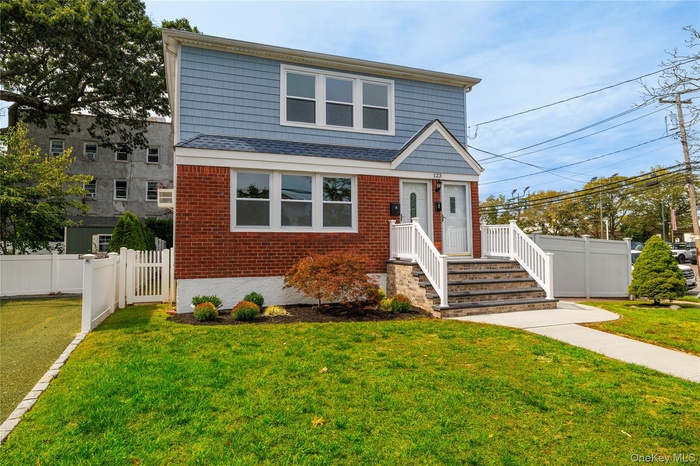View of front facade featuring a shingled roof, a gate, and brick siding
