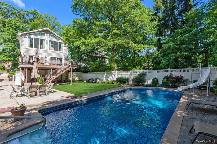 View of pool with a water slide, stairway, a patio, and a wooden deck