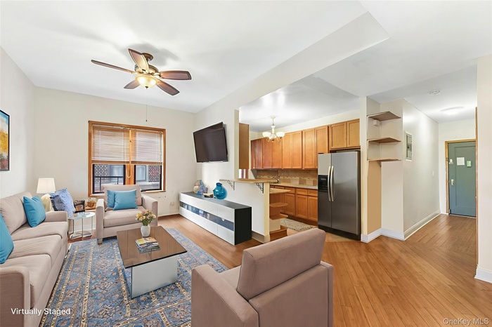Living room featuring light wood-type flooring, ceiling fan, and a chandelier