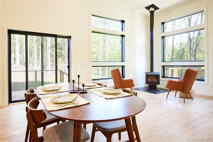 Dining room featuring a wood stove, light wood-type flooring, and a towering ceiling