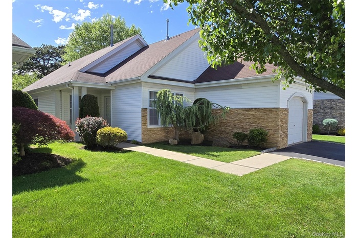 View of front of property with a front yard, an attached garage, asphalt driveway, and a shingled roof