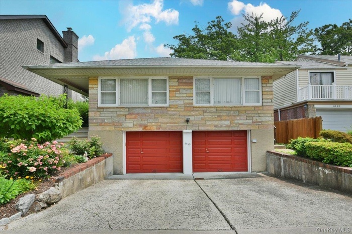 View of front facade featuring stone siding, a garage, and concrete driveway