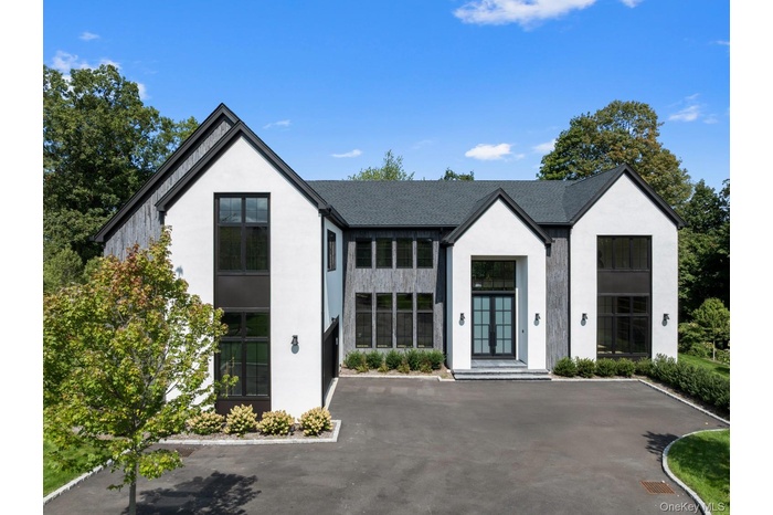 View of front facade with stucco siding and roof with shingles