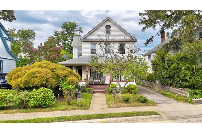 View of front of property featuring a porch, driveway, and roof with shingles