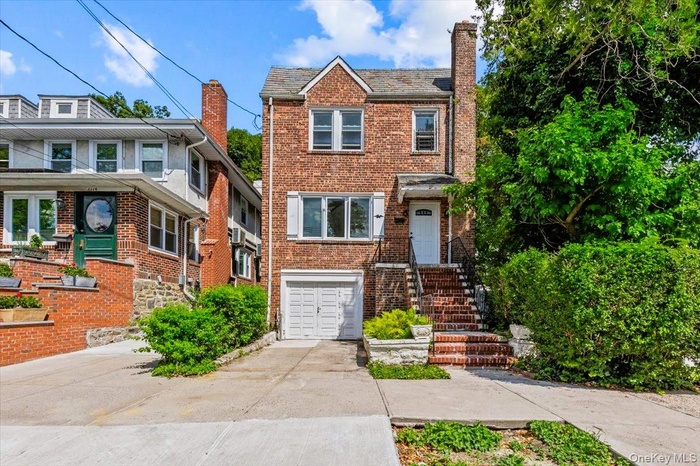 View of front of house featuring a garage, concrete driveway, brick siding, a chimney, and a high end roof