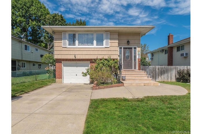 View of front of home featuring brick siding, driveway, and a garage
