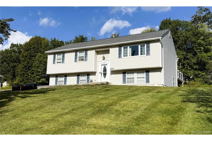 Split foyer home with a front lawn and roof with shingles