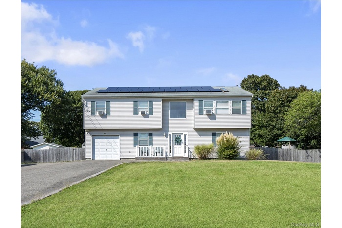 Colonial inspired home featuring solar panels, driveway, and a garage