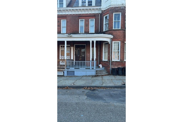 Property entrance with a porch, brick siding, a high end roof, and mansard roof