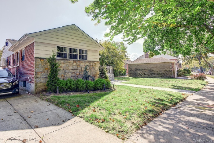 View of front of home with a front yard, brick siding, and stone siding