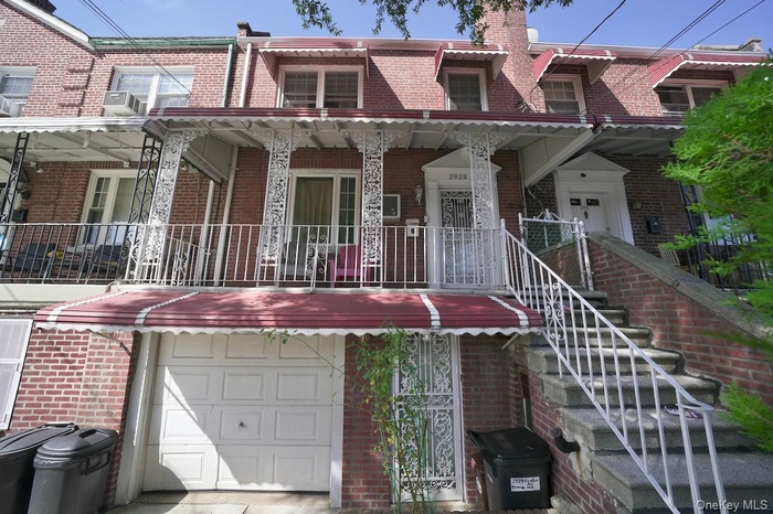 View of front of house with brick siding, a chimney, a garage, and stairs