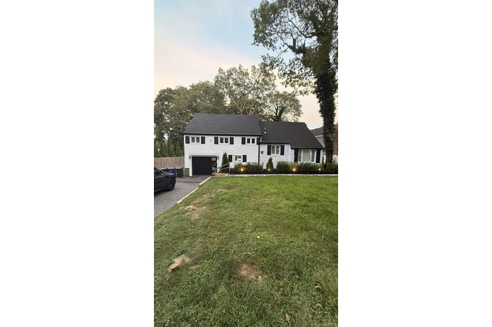 View of front of property with driveway and a lawn