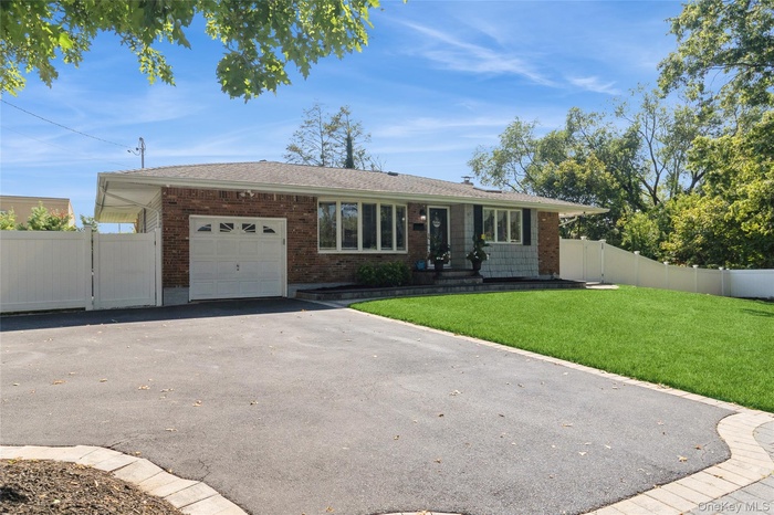 Single story home with a gate, an attached garage, asphalt driveway, brick siding, and roof with shingles