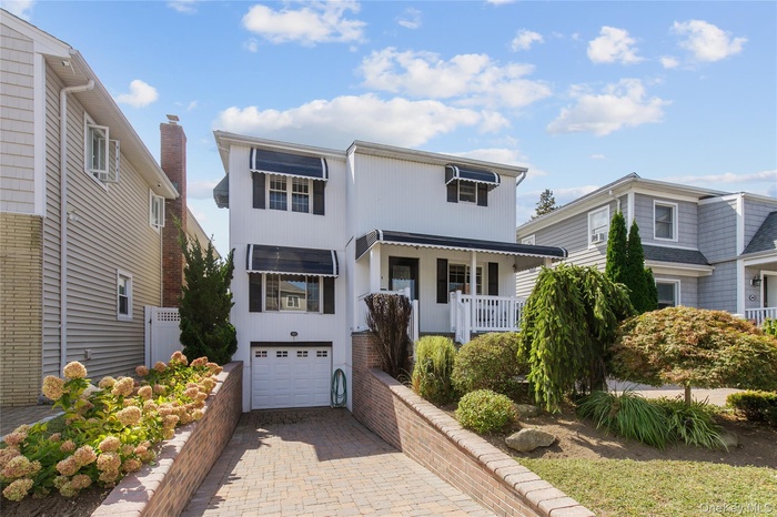 View of front of home featuring covered porch, an attached garage, and decorative driveway
