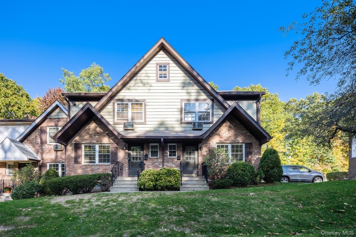 View of front of property with brick siding, a front lawn, and a porch