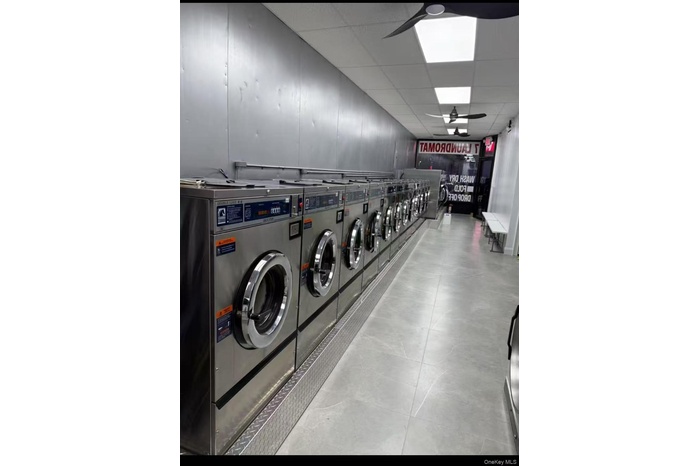 Communal laundry room with separate washer and dryer and light tile patterned flooring