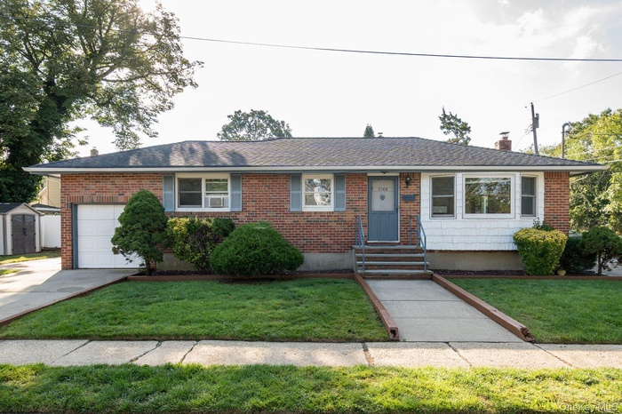 Ranch-style home featuring brick siding, a chimney, a front lawn, and an attached garage