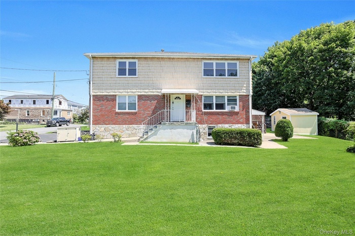 View of front facade with an outdoor structure, brick siding, and a front yard