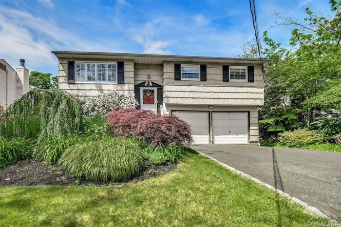 High ranch home with driveway and an attached garage.