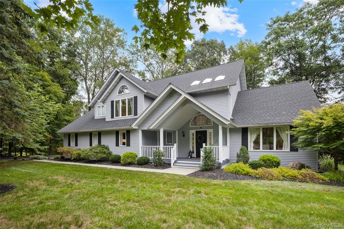 Traditional home featuring roof with shingles, covered porch, and a front lawn