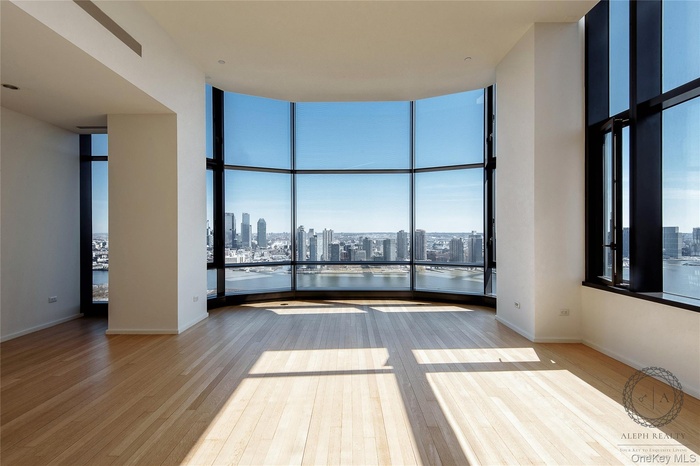 Unfurnished room with baseboards, a wall of windows, wood finished floors, and a view of city