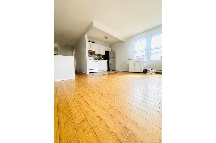 Kitchen with open floor plan, white cabinets, beam ceiling, light wood-style floors, and gas range gas stove